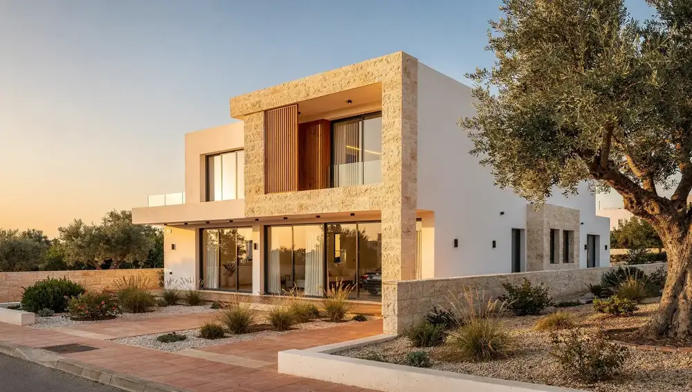 Modern two-storey stone villa with an olive tree at sunset in Cyprus